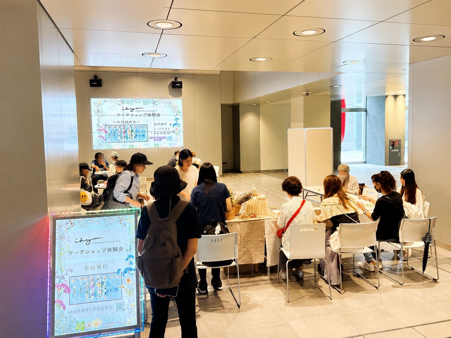 地下歩行空間の広場で開催されたワークショップ体験会。参加者が数名、テーブルを囲んで手を動かしている。
